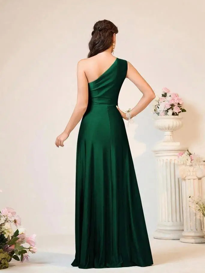 Woman wearing a green one-shoulder dress in an elegant indoor setting.