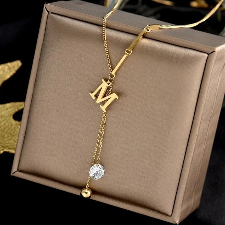 Gold necklace with 'M' pendant on a brown jewelry box | The Tottos