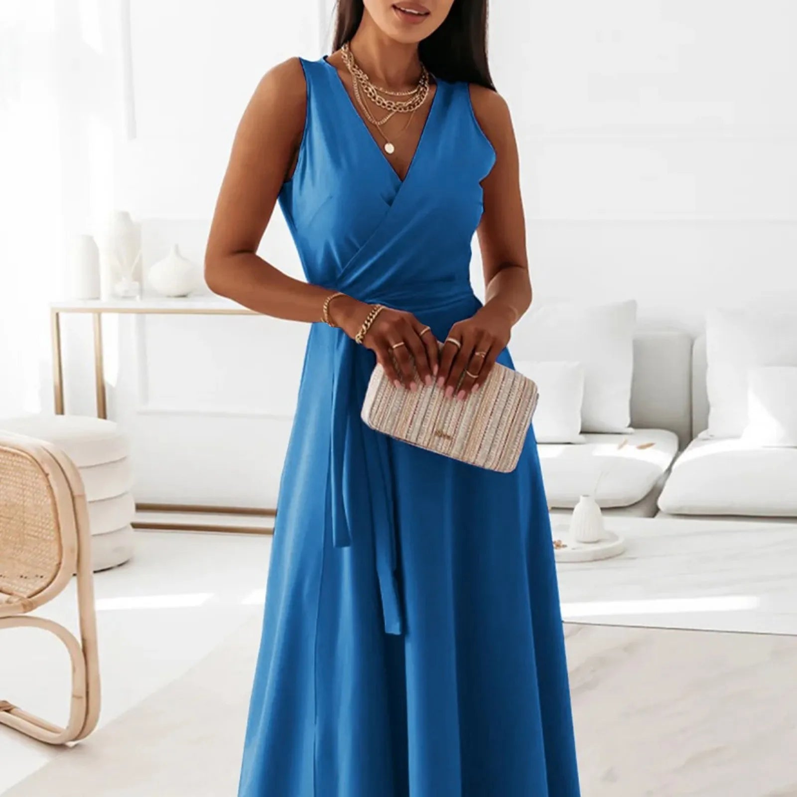 Woman in a blue dress holding a clutch in a modern living room.