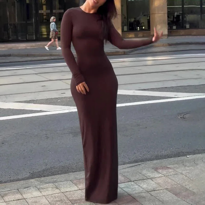 Woman in a brown long-sleeve dress standing on a city street.