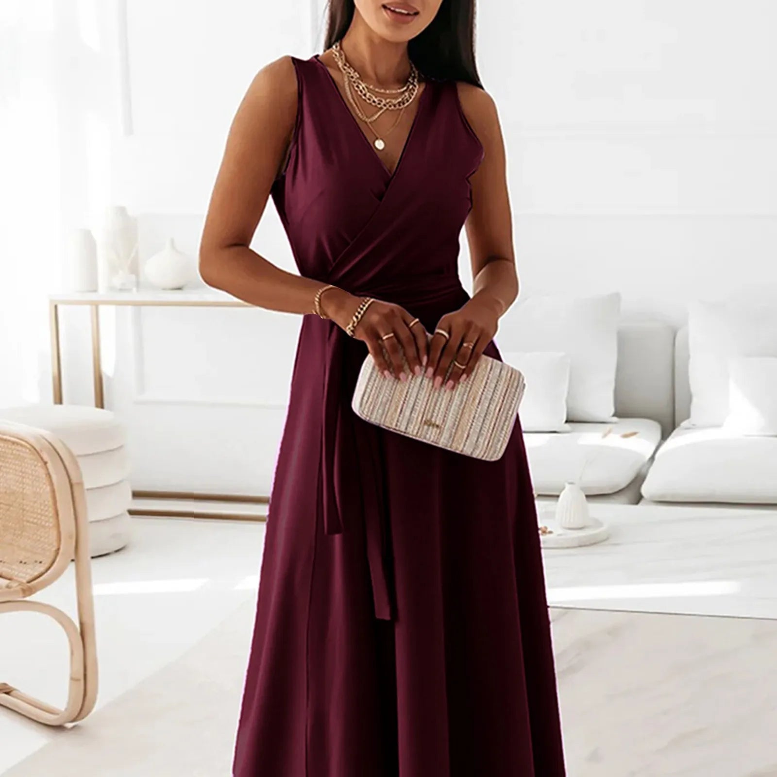 Woman in a burgundy dress holding a clutch in a modern living room.