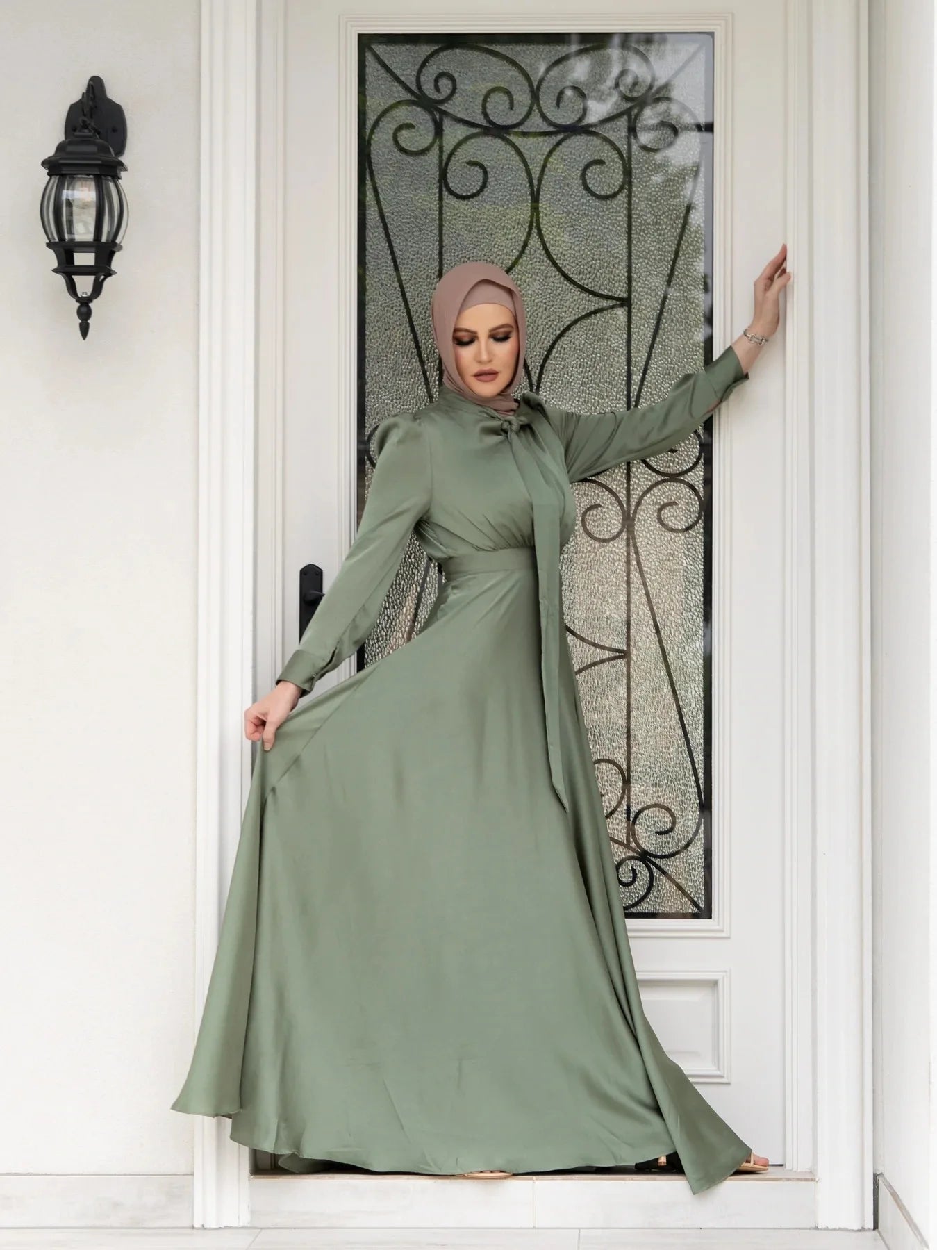 Woman in a green dress standing in front of a decorative door.