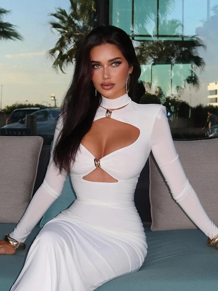 Woman in a white dress with cut-out design sitting outdoors.