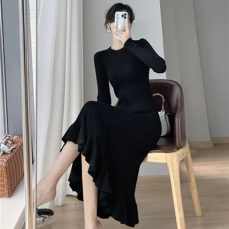 Woman wearing a black elegant dress sitting on a chair in a room.