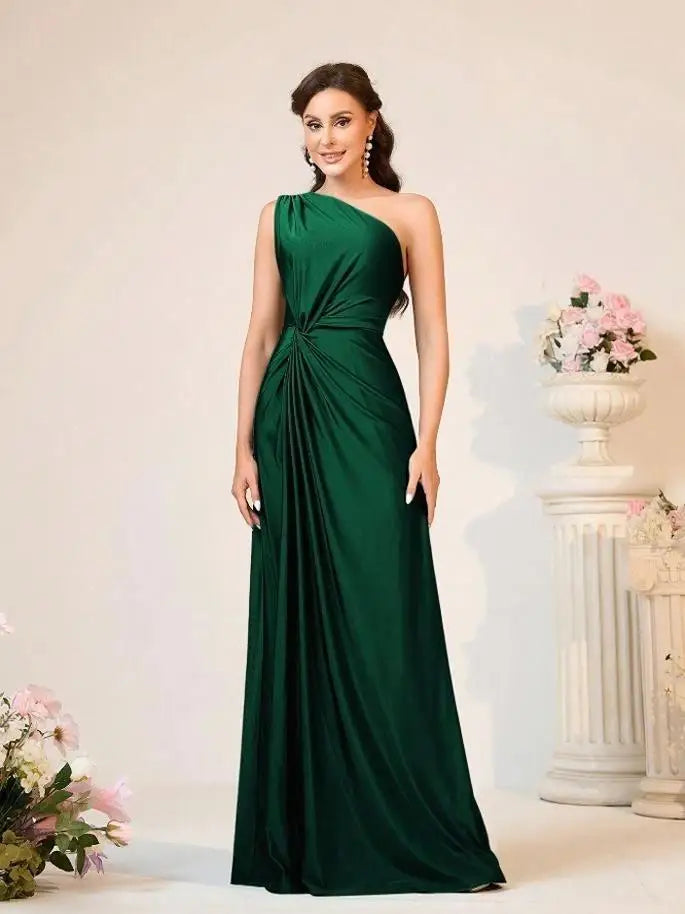 Woman wearing a green one-shoulder dress in an elegant indoor setting.