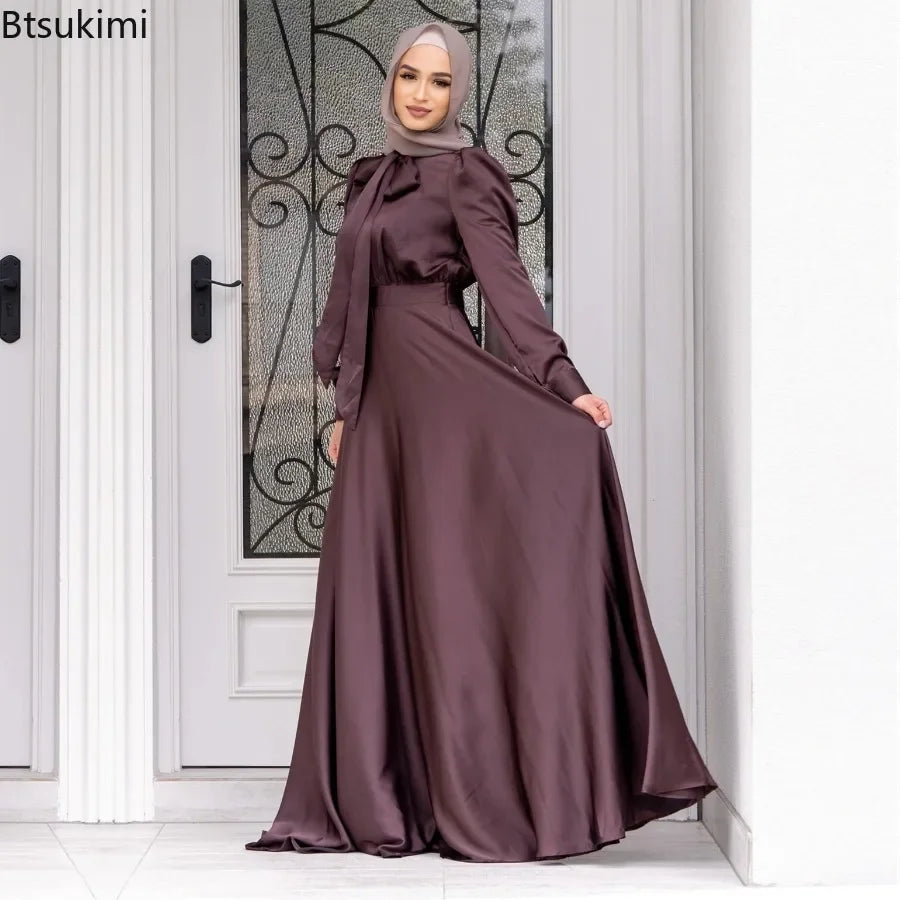 Woman wearing a long, dark purple dress with a matching hijab in front of a decorative door.