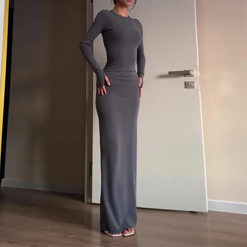 Woman wearing a long gray dress standing in a room with a neutral color scheme.